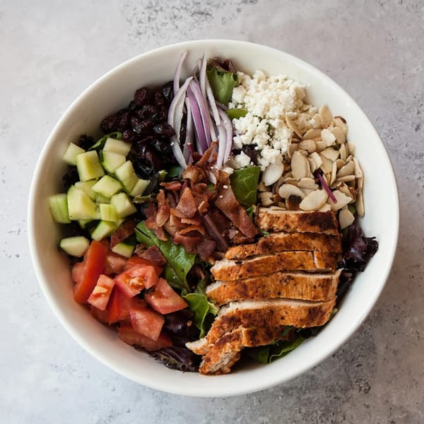 A vibrant salad from Cafe La Tazita with grilled chicken, bacon, feta, almonds, and vegetables.