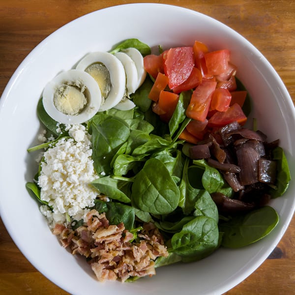 A Cafe La Tazita spinach salad with eggs, tomatoes, feta, bacon, and caramelized onions.